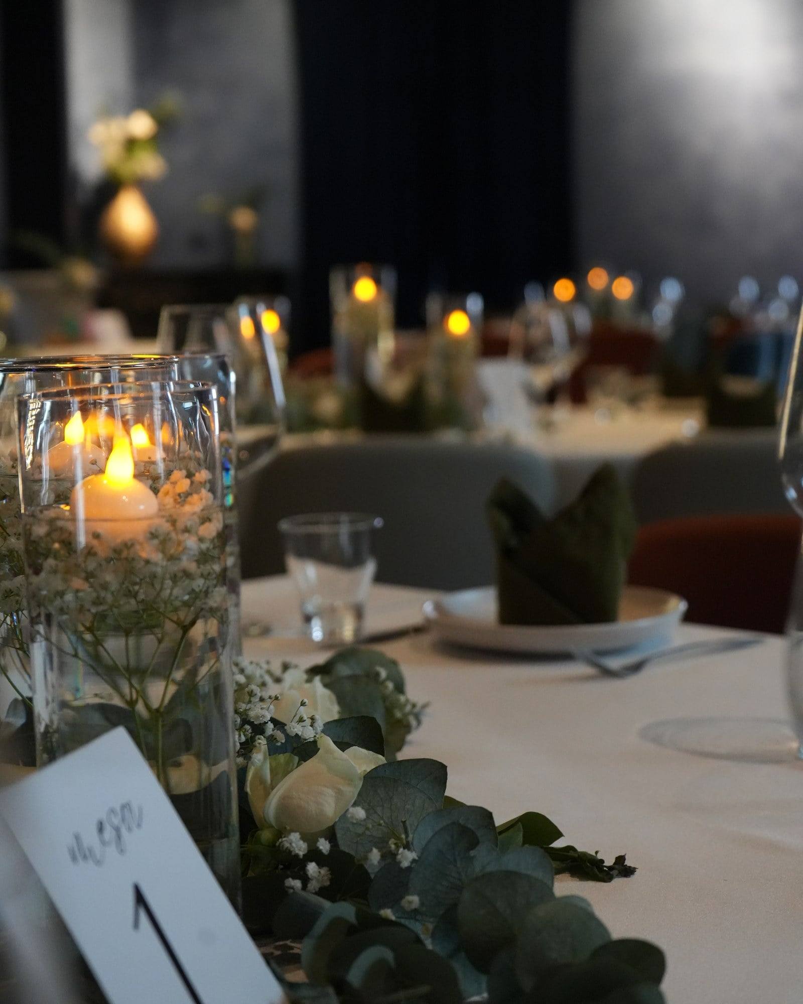 Table centrepiece with floating candles, white roses and eucalyptus