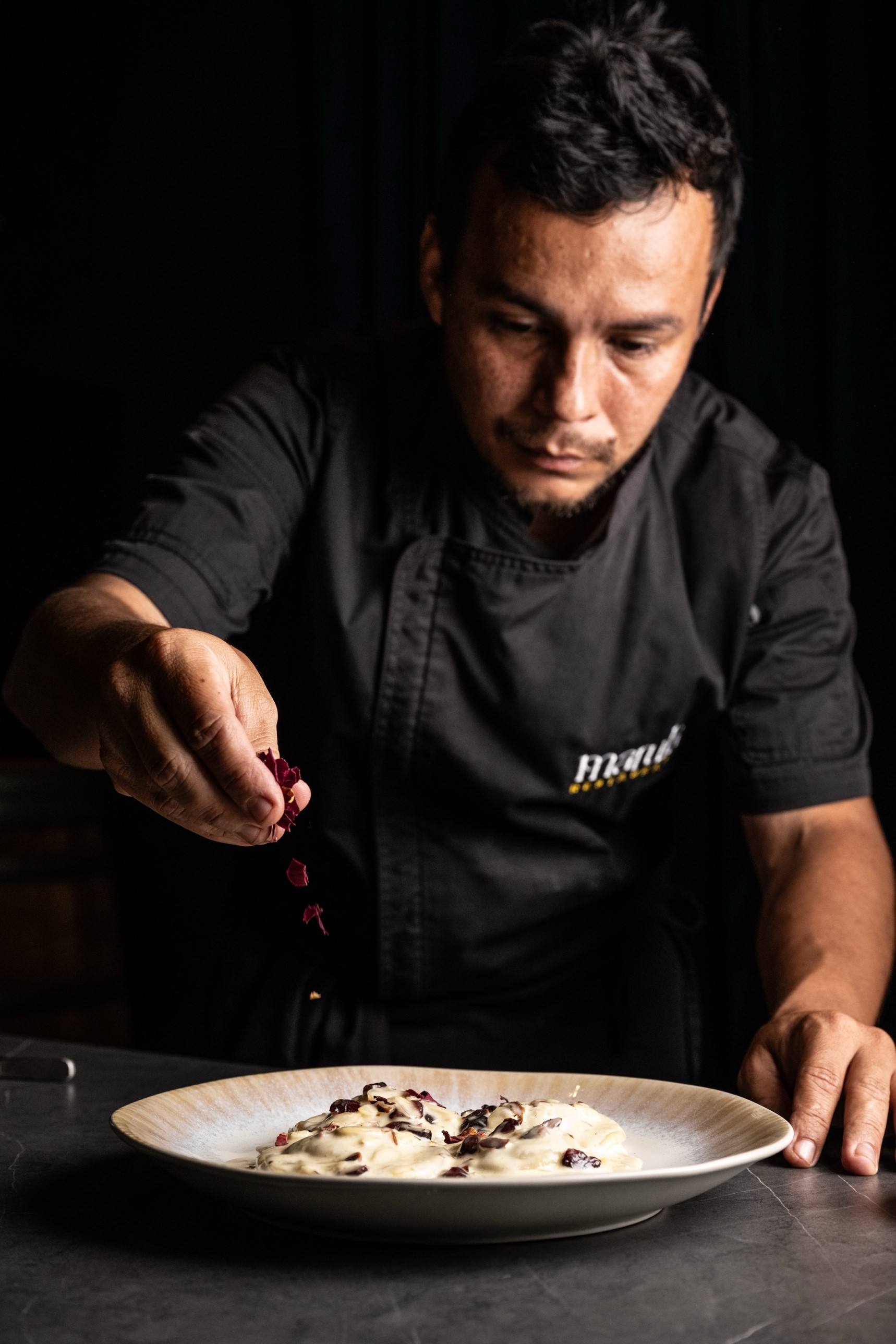 El chef Jeison López terminando un plato con pétalos en la cocina de Marula